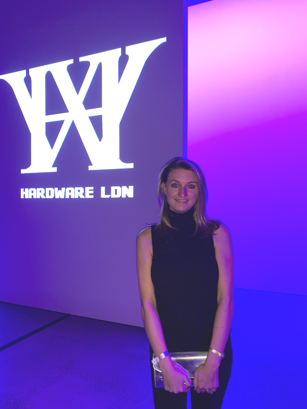 Danielle Newport Fancher at a Fashion Week event, standing before an illuminated venue wall