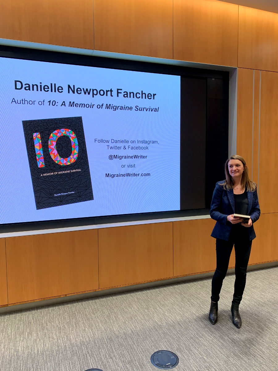 Danielle beside a presentation screen showing the cover of 10, holding a copy of the book
