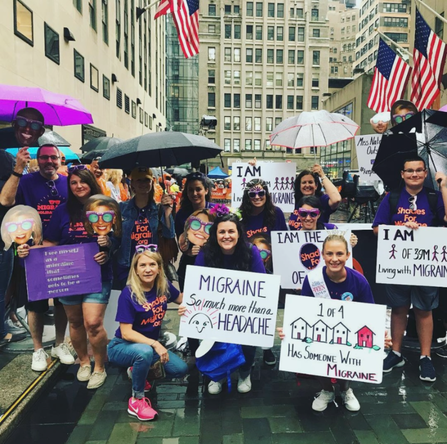 A Shades for Migraine group outside the Today Show plaza in the rain, holding handmade signs reading Migraine: so much more than a headache