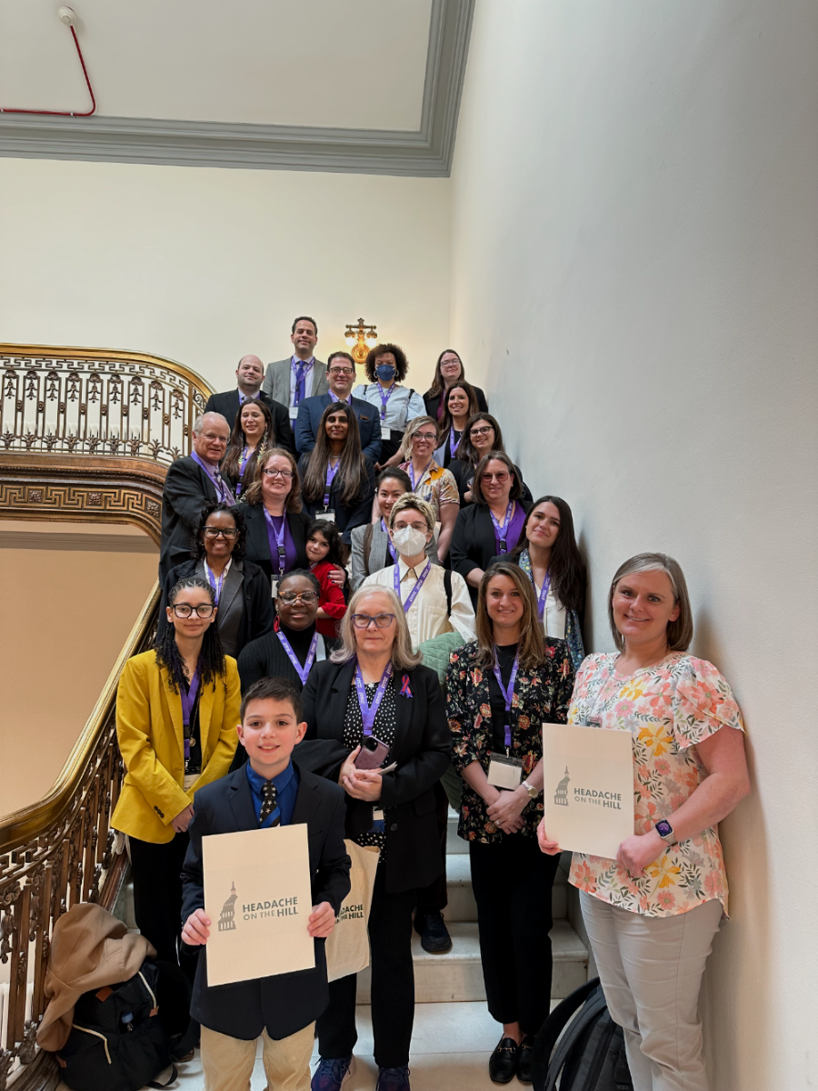A Headache on the Hill advocacy team gathered on a staircase inside a Congressional office building, holding Headache on the Hill folders